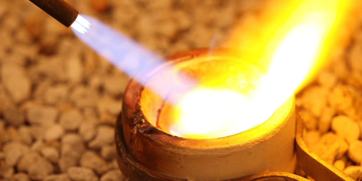 Closeup of a torch being used to heat up material in a crucible